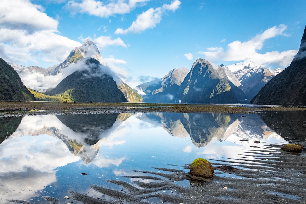 body of water near mountain under blue sky during daytime Milford Sound