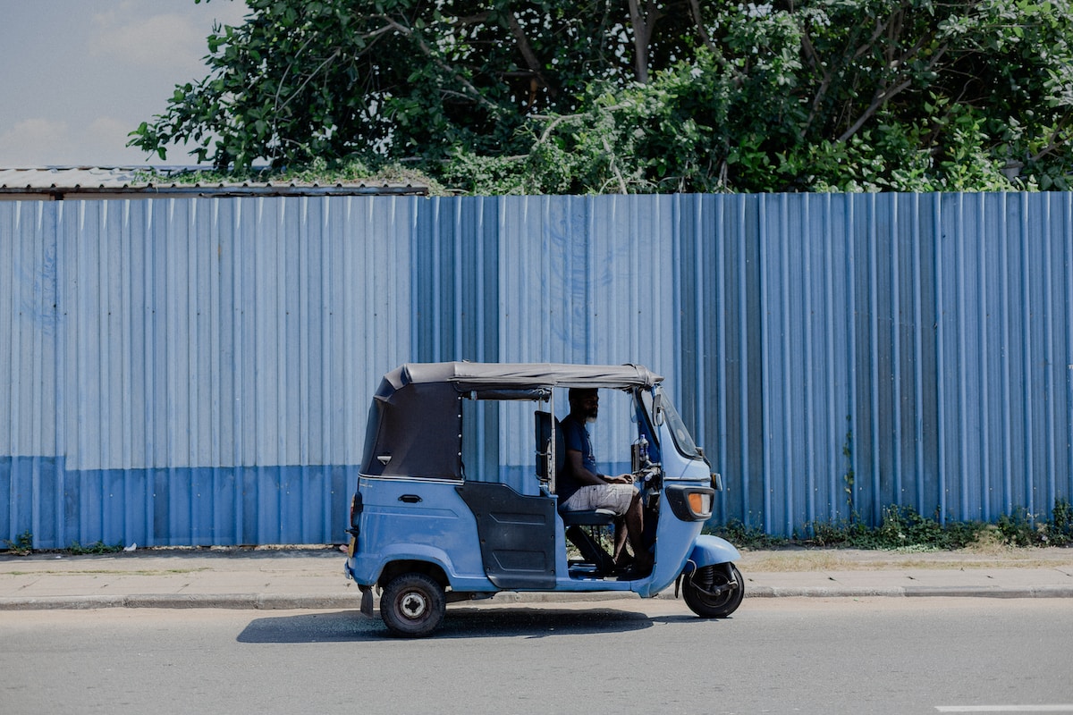 blue and white auto rickshaw parked beside white wall - Colombo