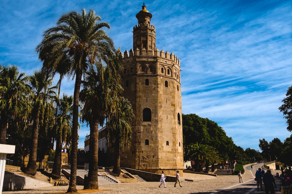 a tall tower with a clock on the top of it - Torre del Oro Seville, Spain