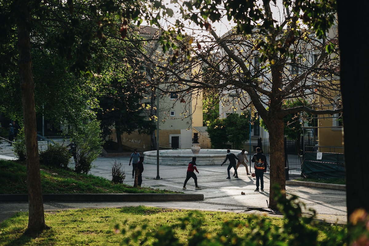 a group of people walking around a park Athens