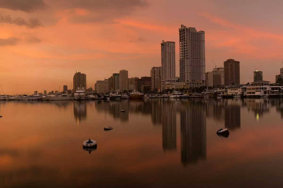 white boat on water near city buildings during sunset in Manila