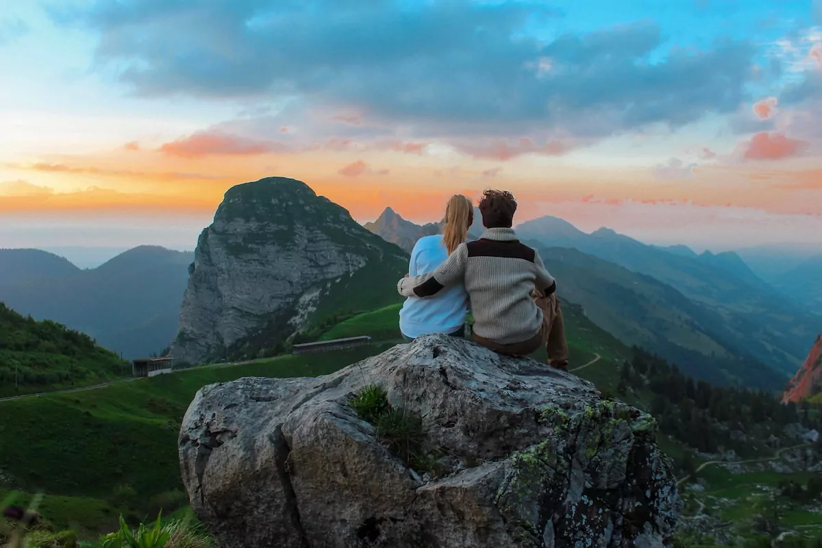 couple sitting on rock facing mountain view Geneva hiking