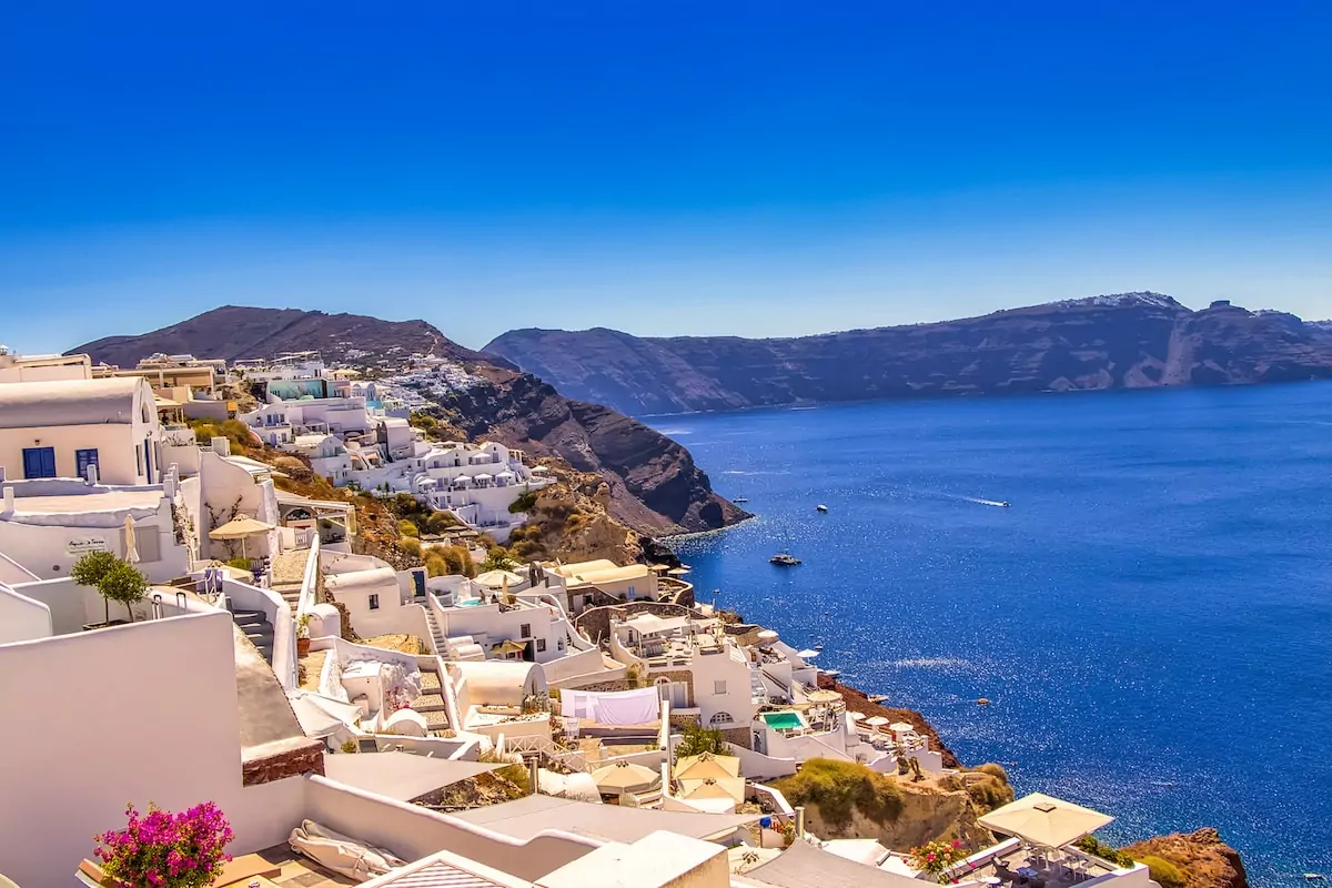 white and brown houses near blue sea under blue sky during daytime - Santorini