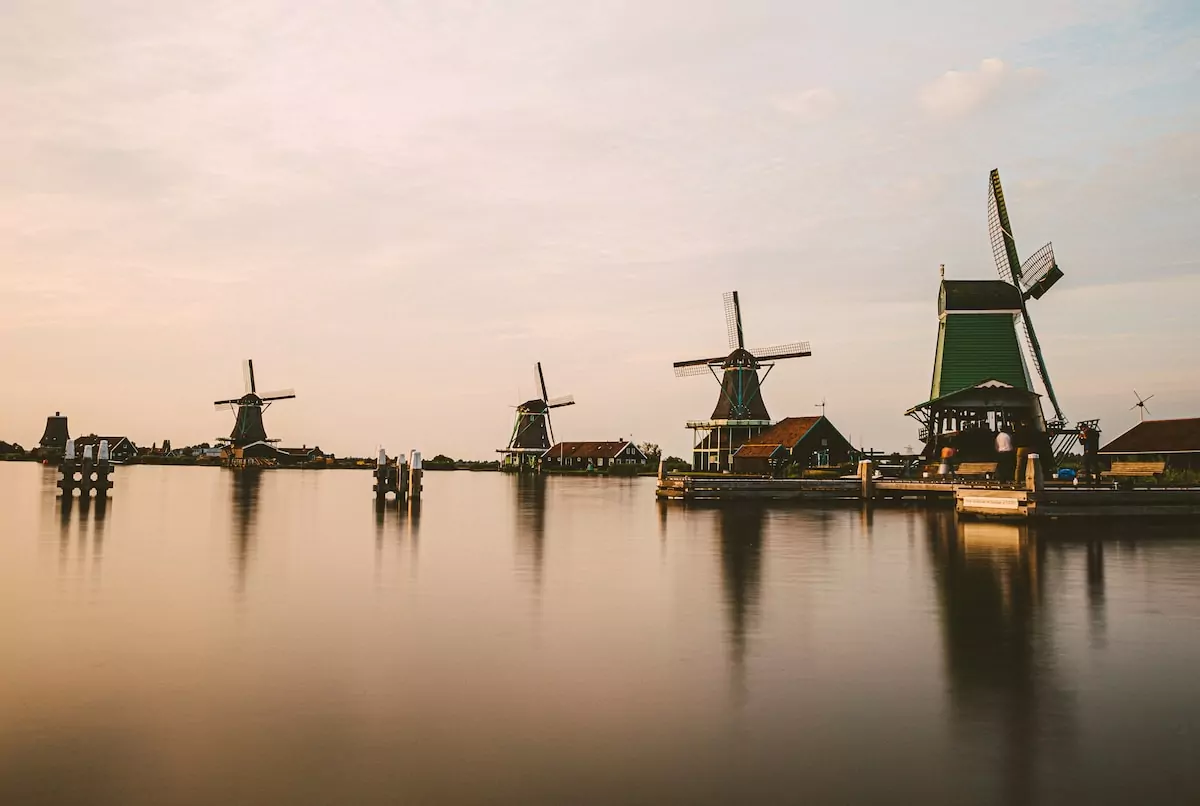 a group of windmills sitting on top of a lake - Amsterdam Netherlands