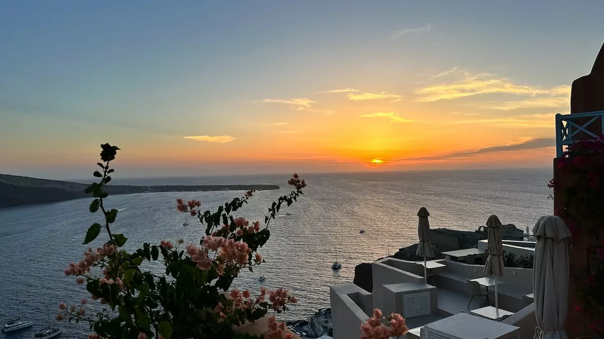 the sun is setting over the ocean and buildings - Sunset view from Oia Santorini