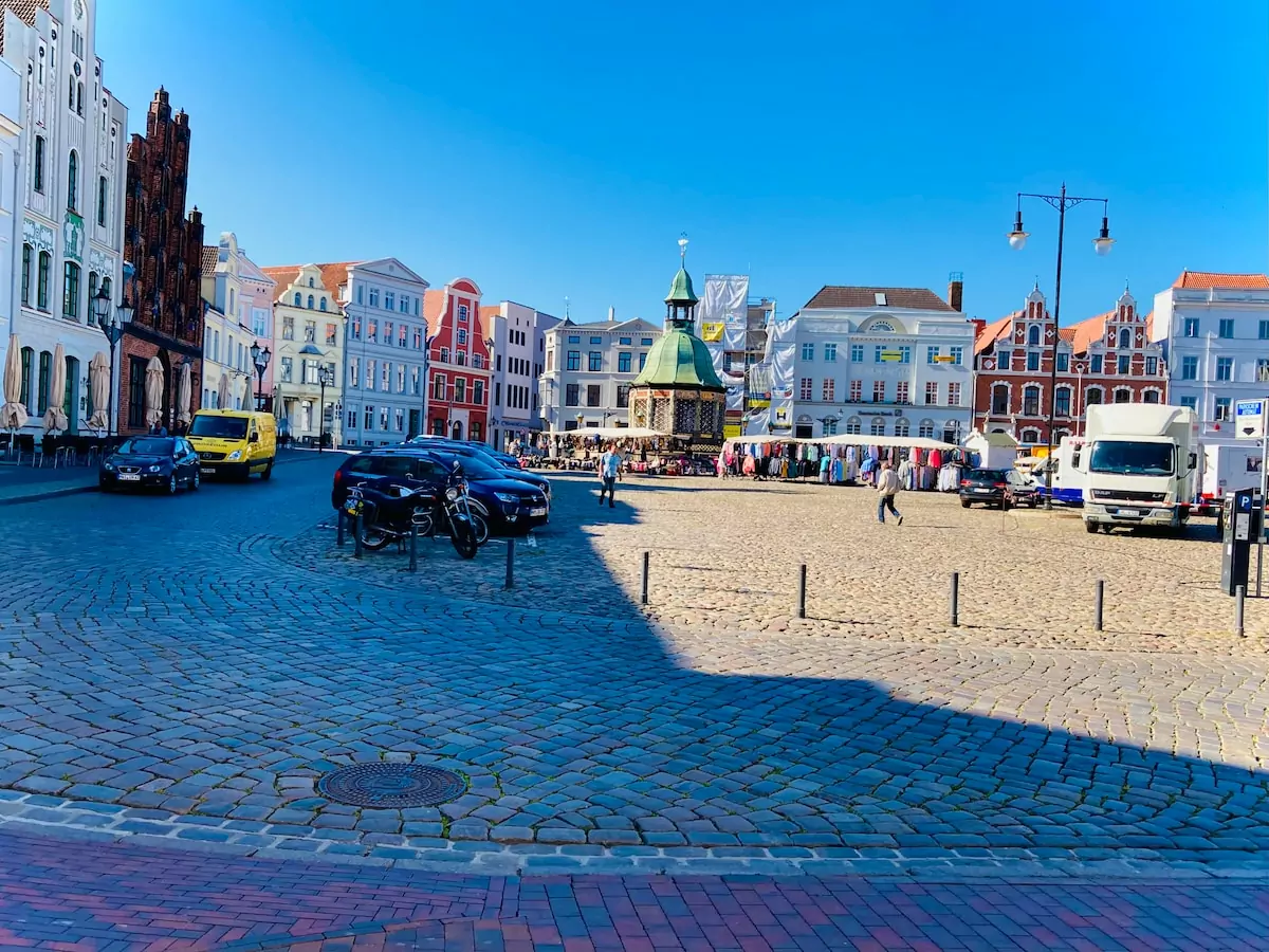 a brick road with cars and buildings on either side of it - Old Town Market Place