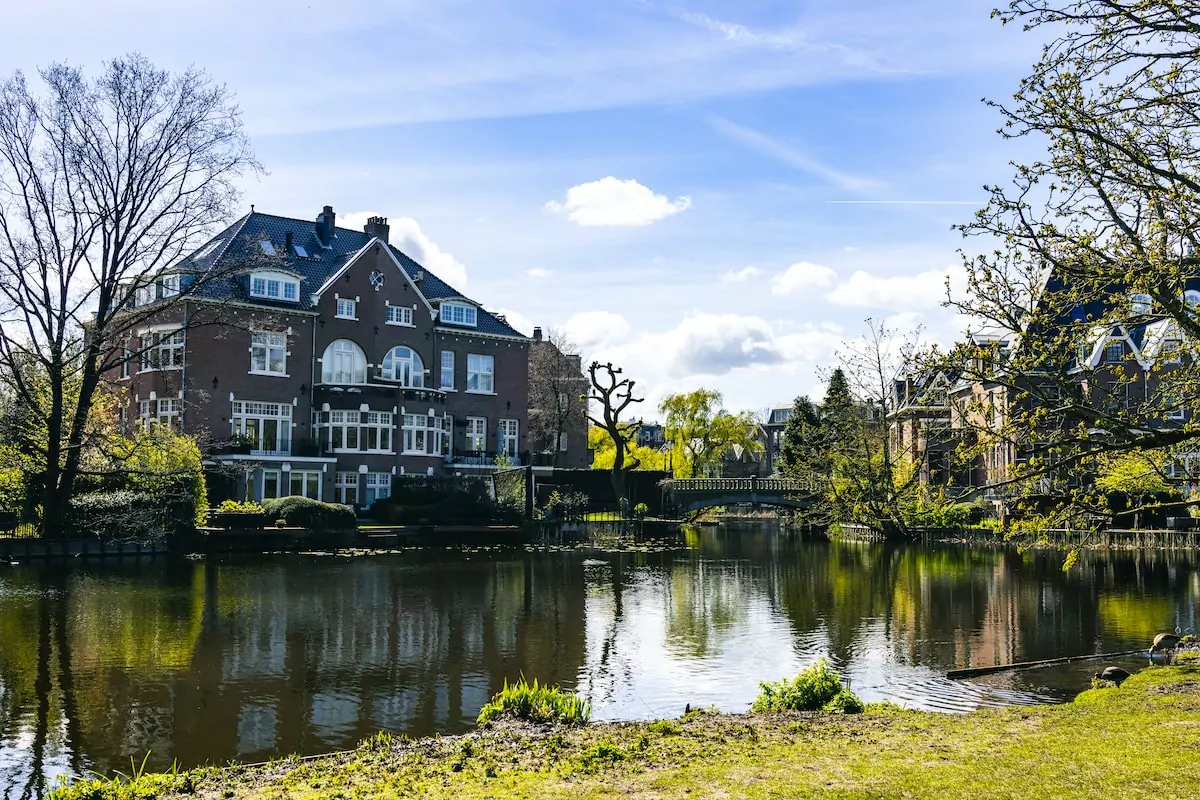 a large house sitting on the side of a river - Vondelpark Amsterdam Netherlands