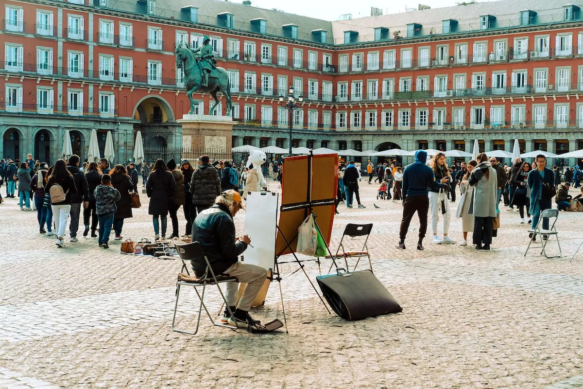 a man sitting in a chair in front of a building - Stroll Plaza Mayor, Madrid, Spain