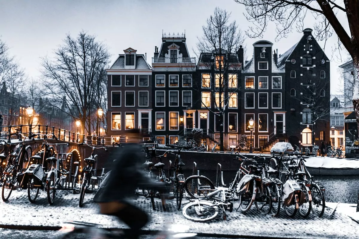 bicycles parked on road near building during night time - Biking along the canals of Amsterdam