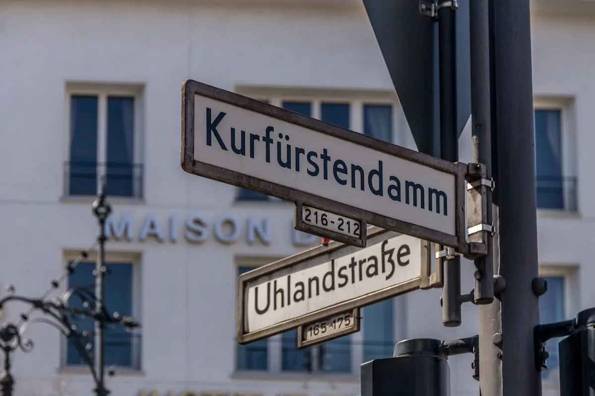 a close up of a street sign hanging from a pole - Kurfürstendamm