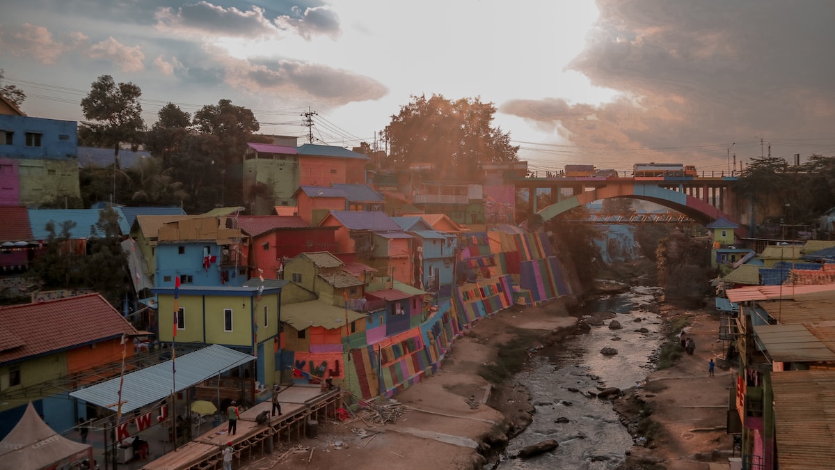 blue red and white concrete building near green trees under white clouds during daytime - Malang